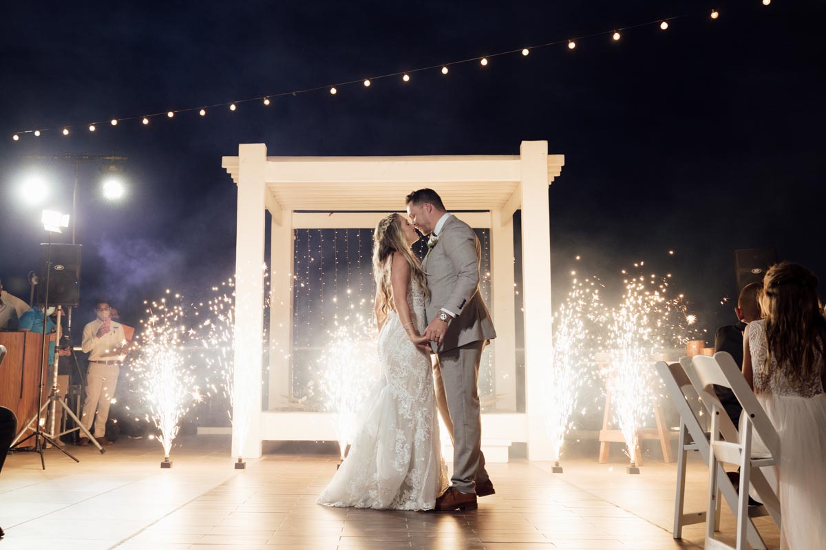 Newlyweds kiss on the dance floor surrounded by fireworks