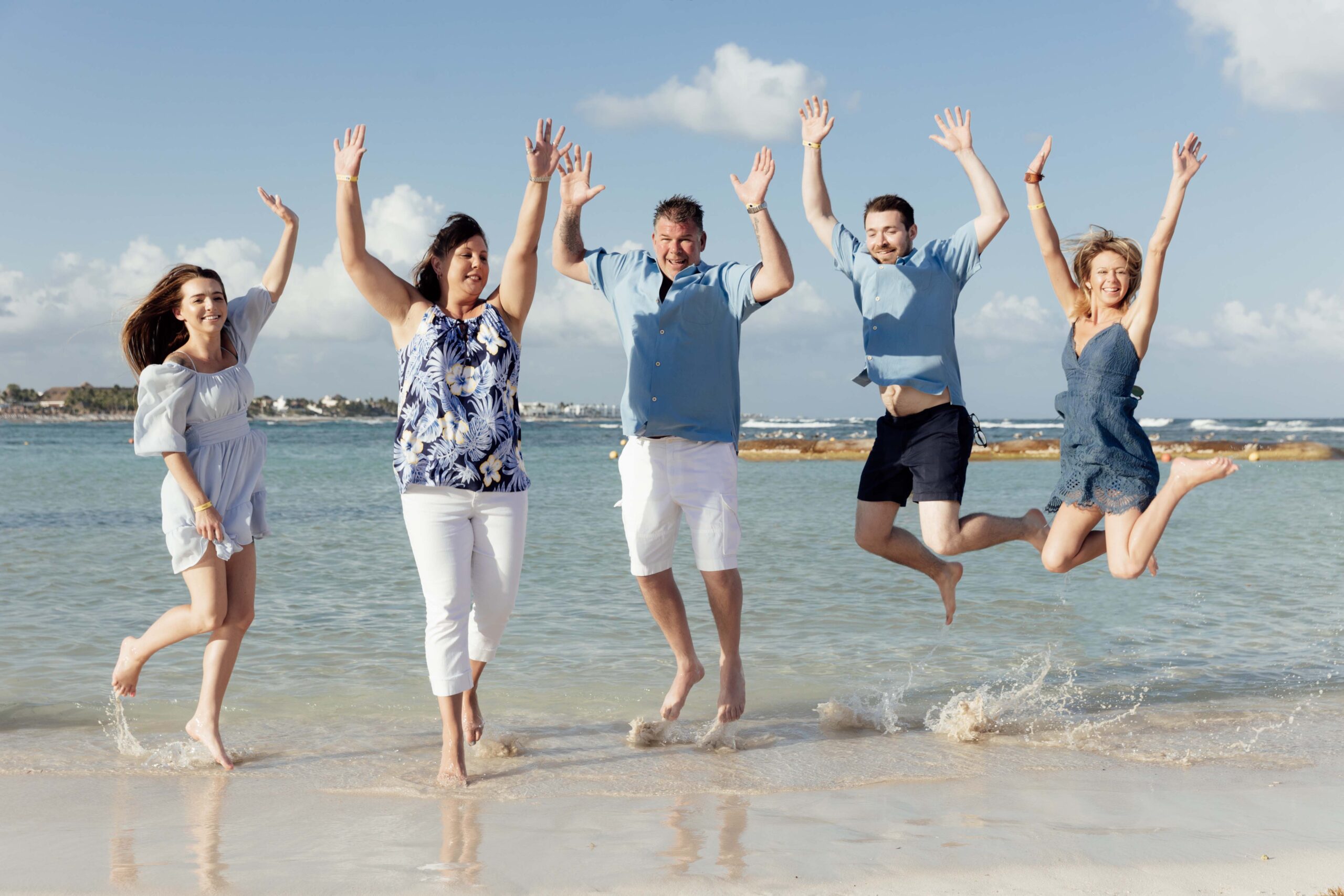 Family jumping for joy on the beach at the water's edge