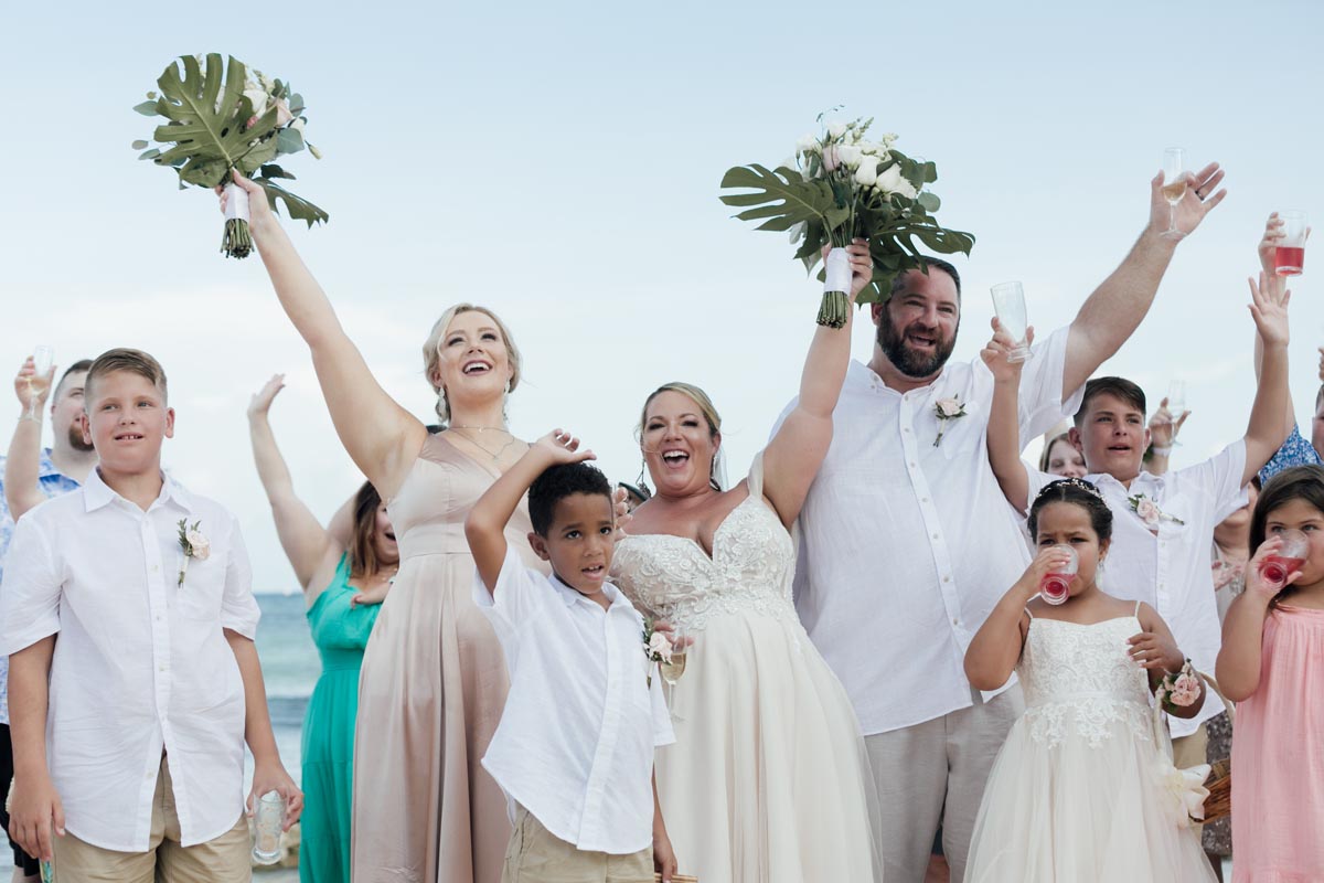 Newlyweds cheer with family on the beach