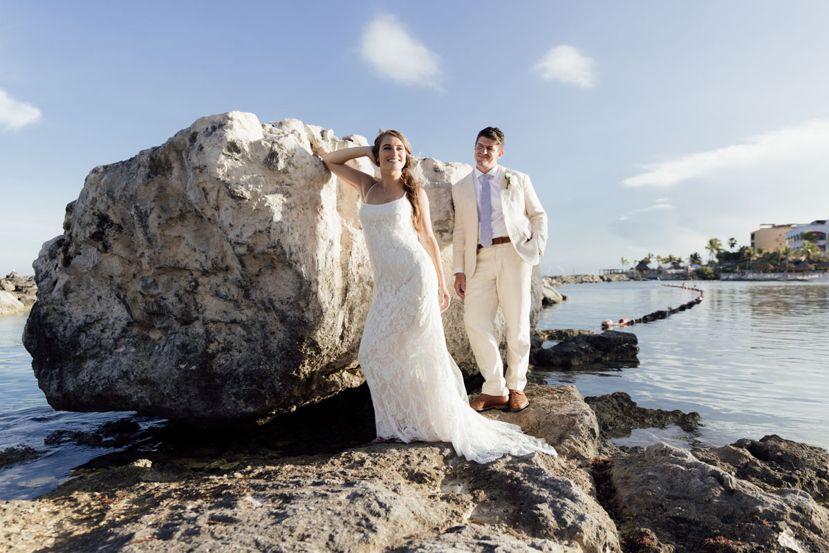 Newlyweds pose on oceanside rock