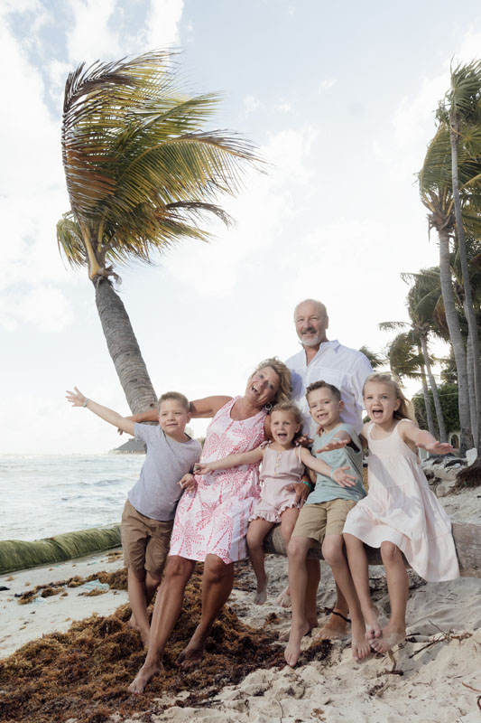 Grandparents sit on palm trunk with their precious grandkids