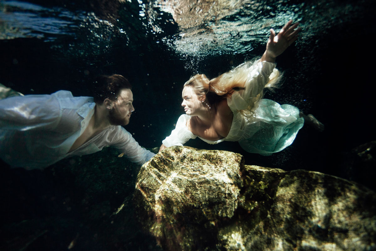 Newlyweds float towards each other for an underwater kiss