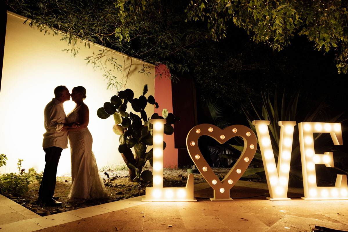 Newlyweds kiss beside Love sign