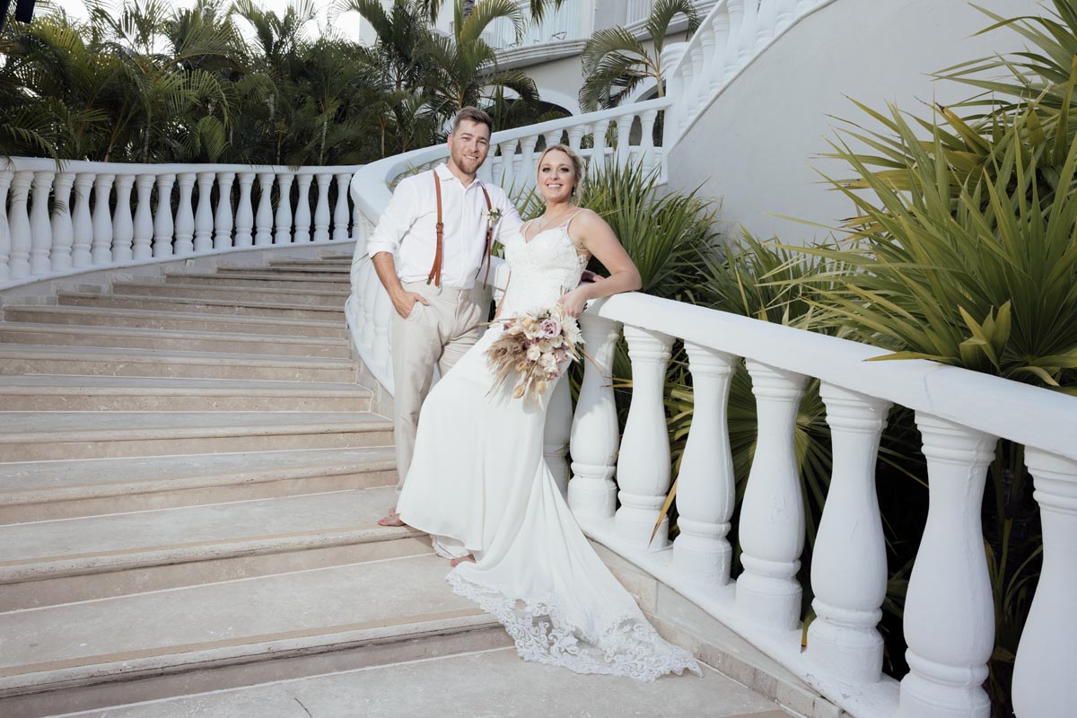 Newlyweds lean against the railing on steps of Royalton