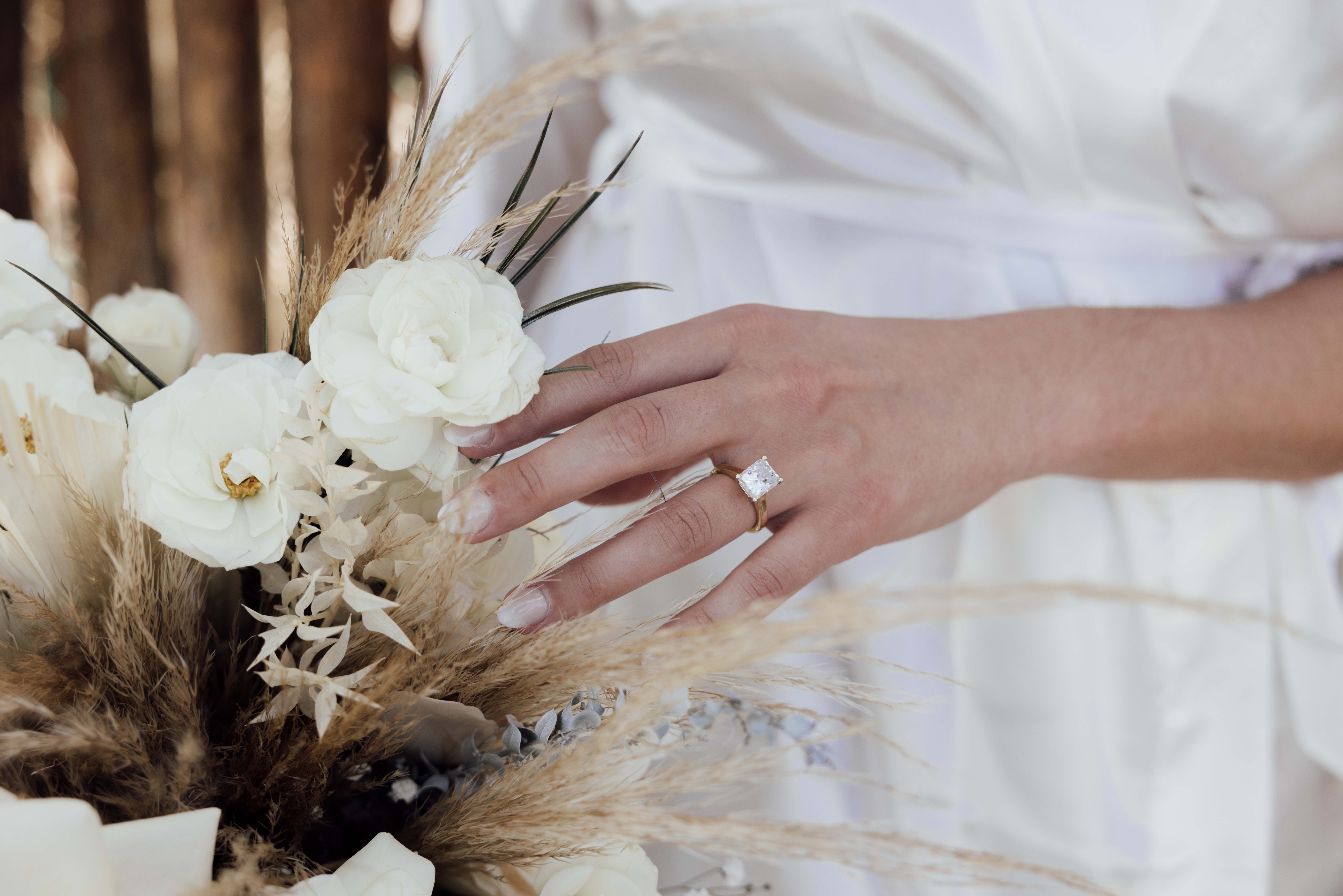 Bride touches bouquet wearing her diamond