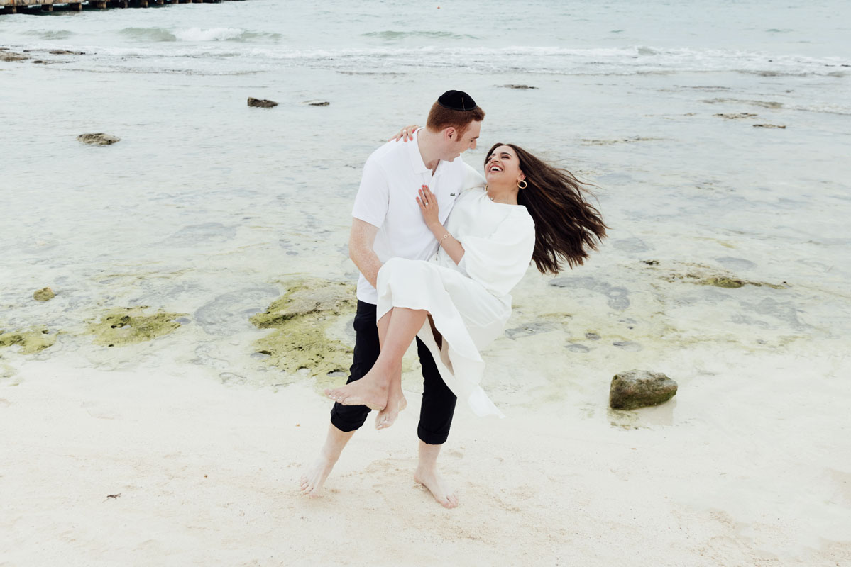Husband swings his wife around on the beach, her hair flying!