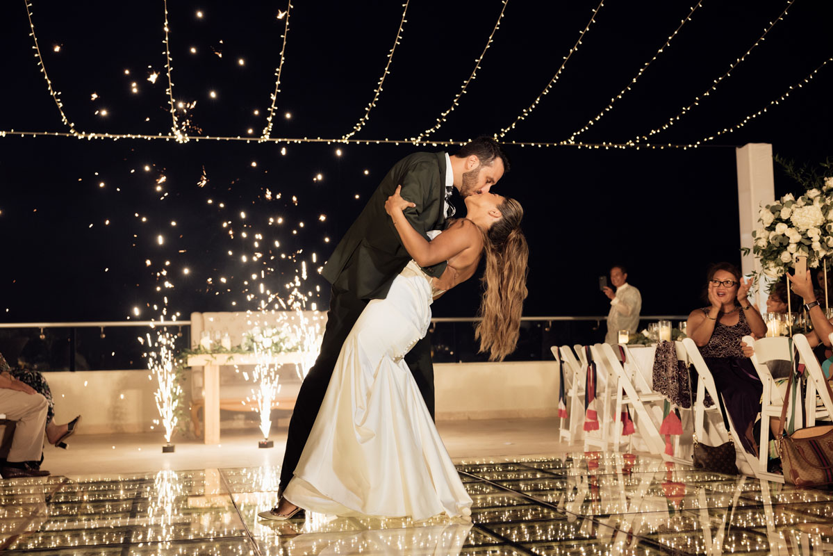 Newlyweds finalize their first dance with an epic kiss while dipping in front of spouting fireworks
