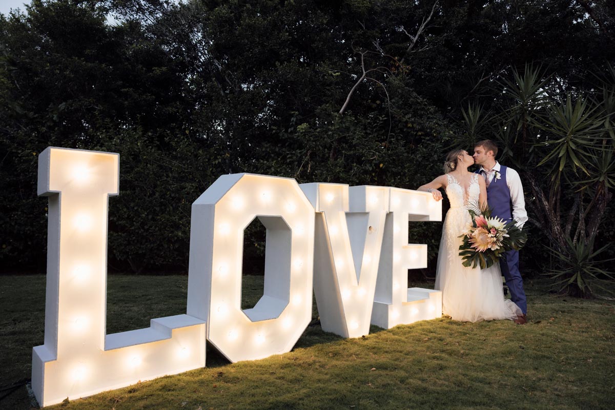 Newlyweds kiss by LOVE sign