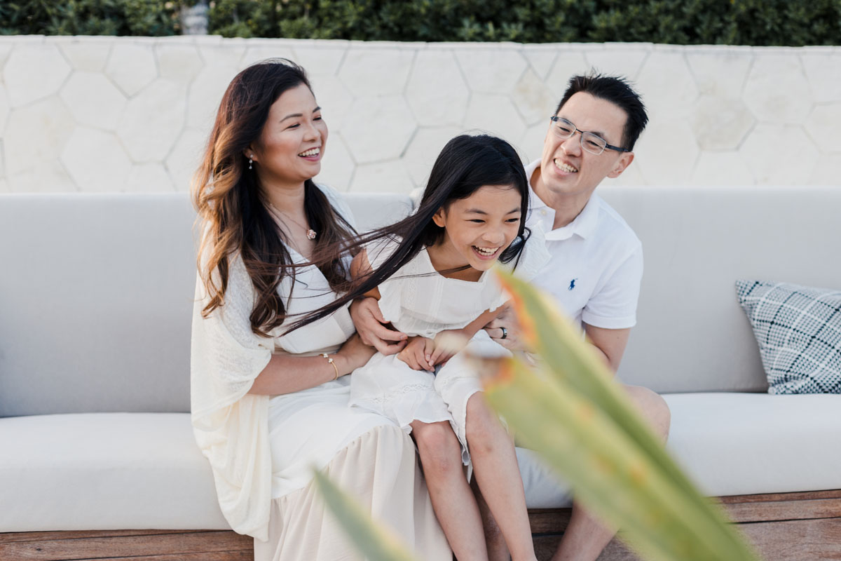 Laughing daughter wiggles out of parents' embrace