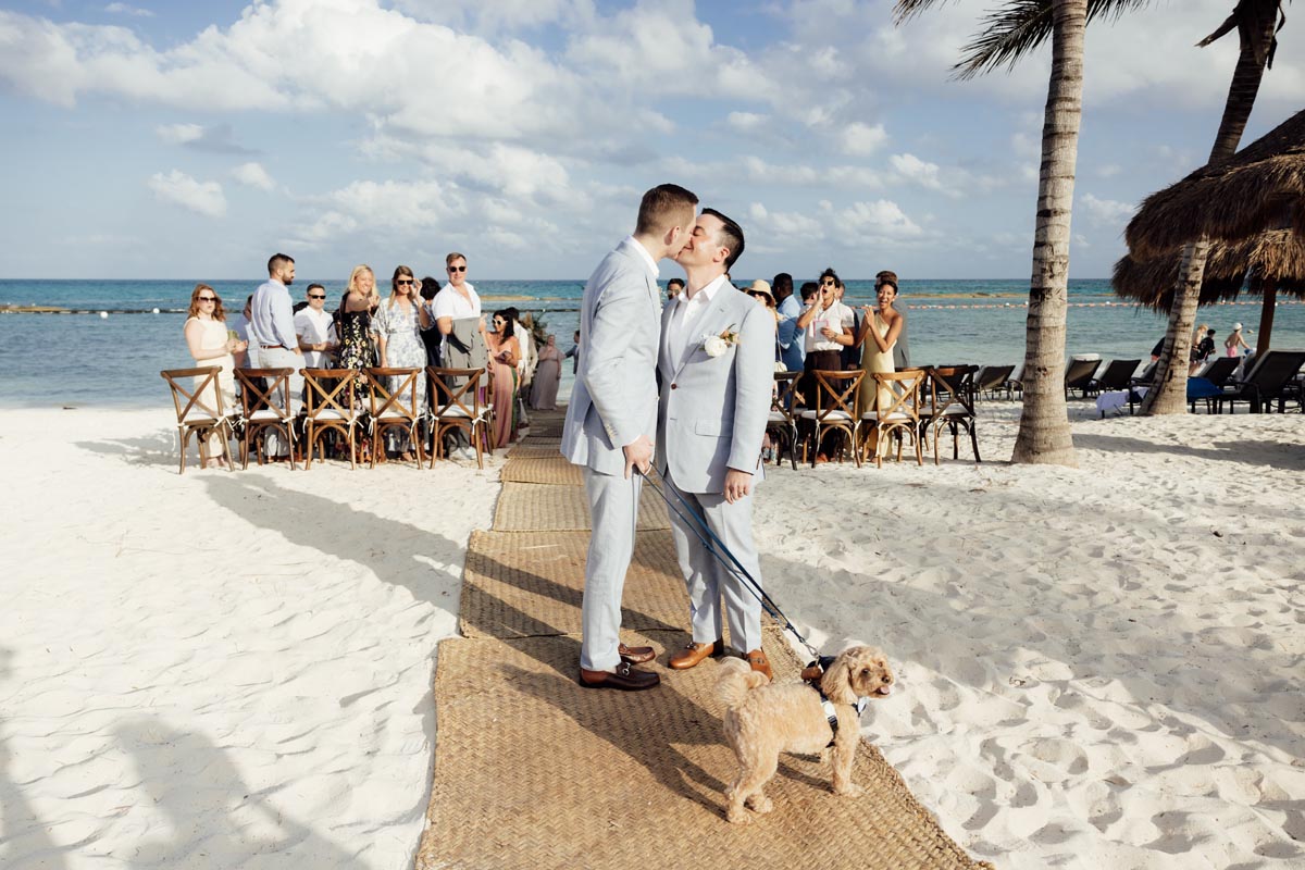 Newlyweds kiss after ceremony, holding their beloved dog