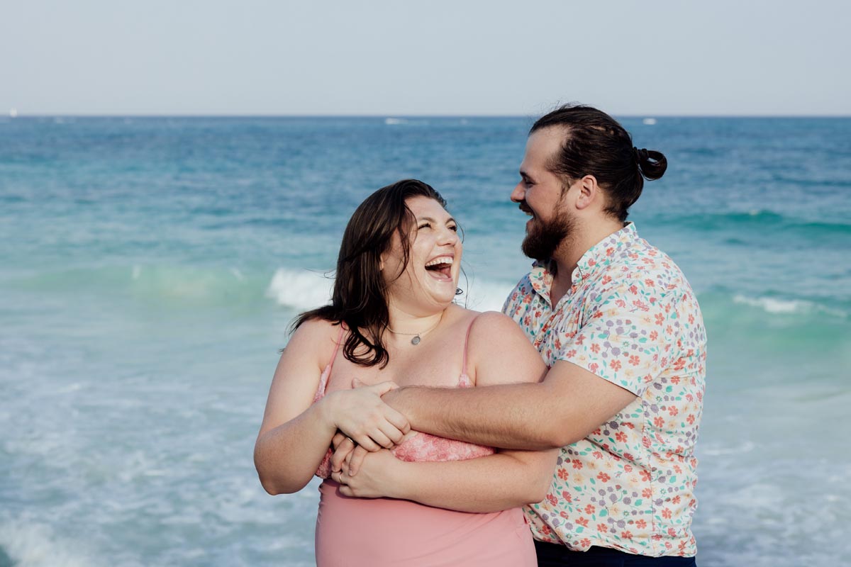Anniversary couple laugh in each others arms on the beach
