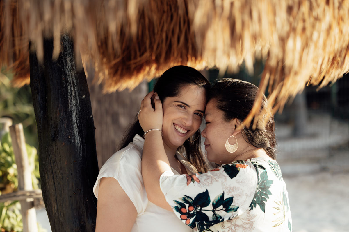 Engaged couple embrace under palapa