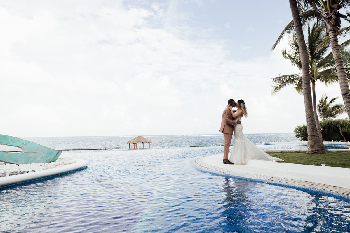 Wedding couple kiss beside the pool next to the Caribbean
