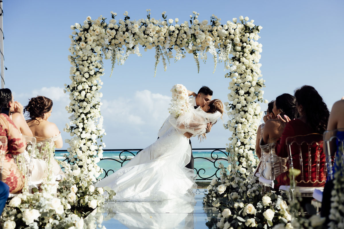 Newlyweds dip in first kiss under elaborate floral arch