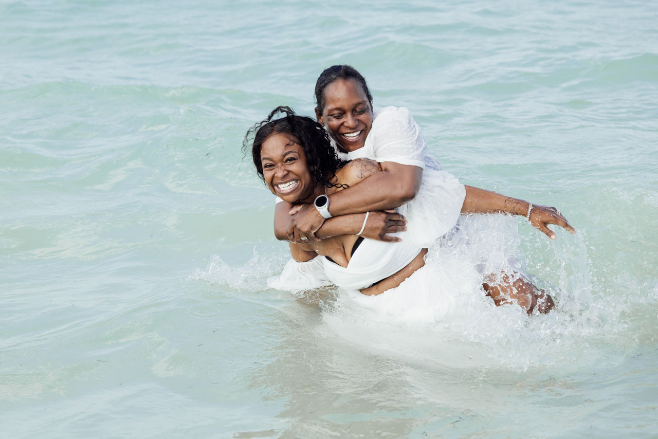 Laughing anniversary couple embrace in the ocean, splashing