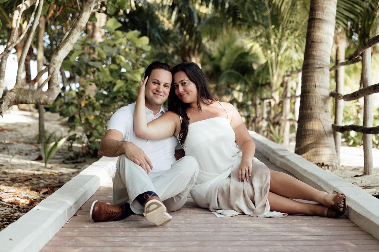Newly engaged couple snuggle while sitting on jungle path
