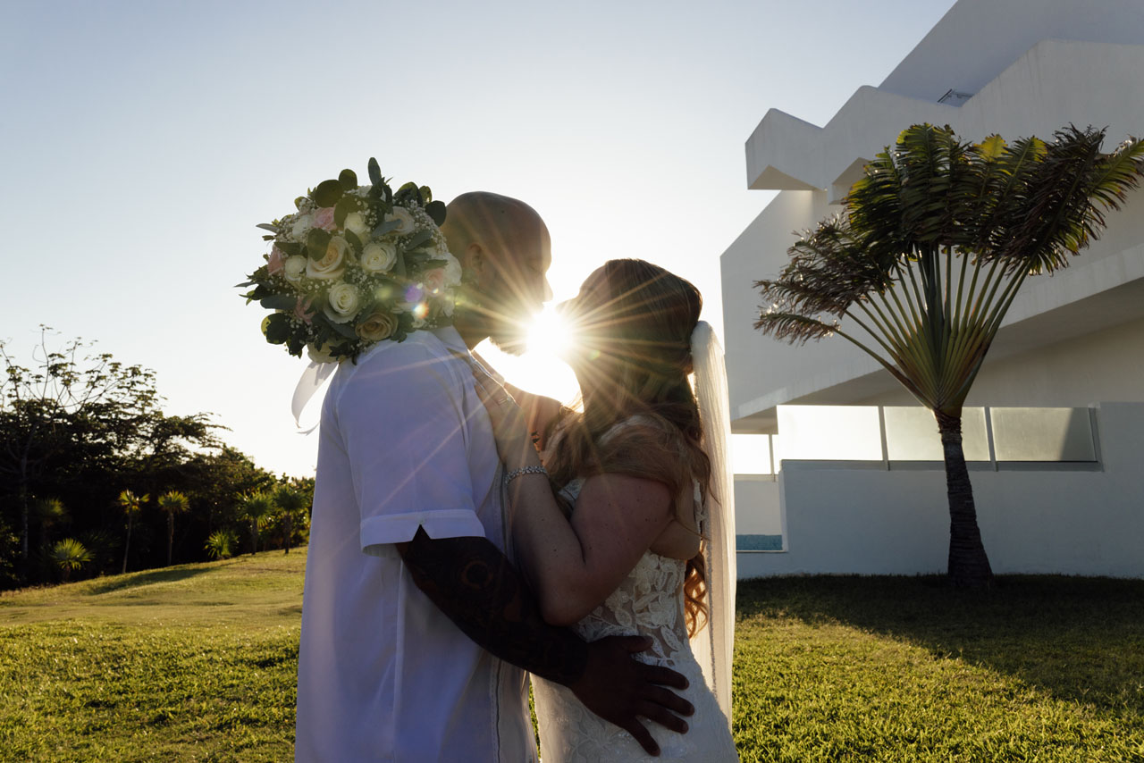 Newlyweds embrace in sunburst silhouette
