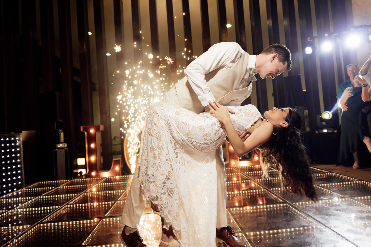 Newlyweds dip in a kiss after first dance in a spray of fireworks