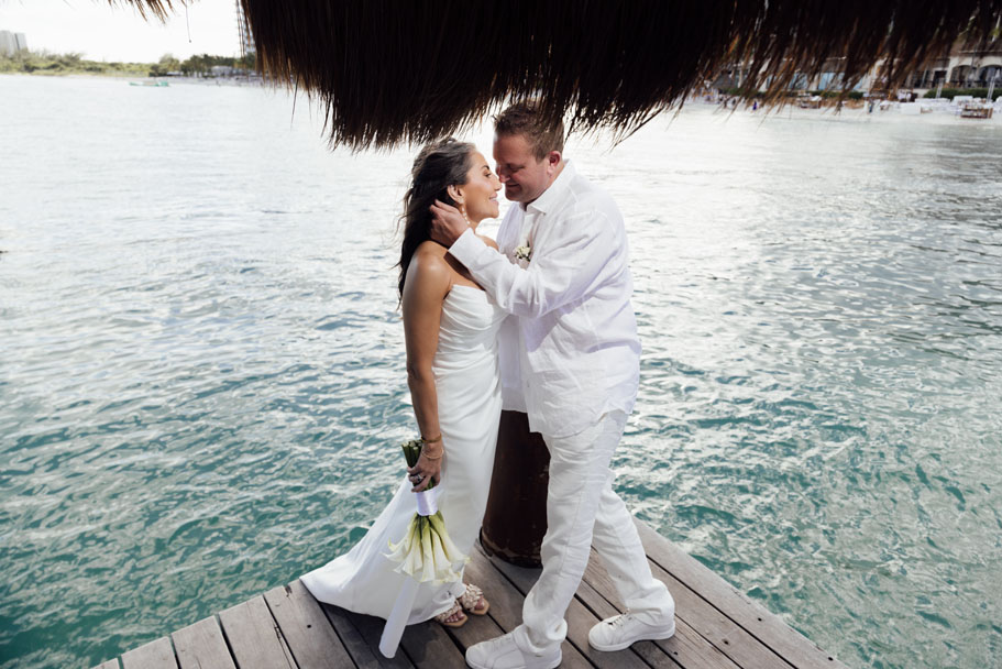 Groom reaches to kiss bride on their ceremony deck overlooking the ocean