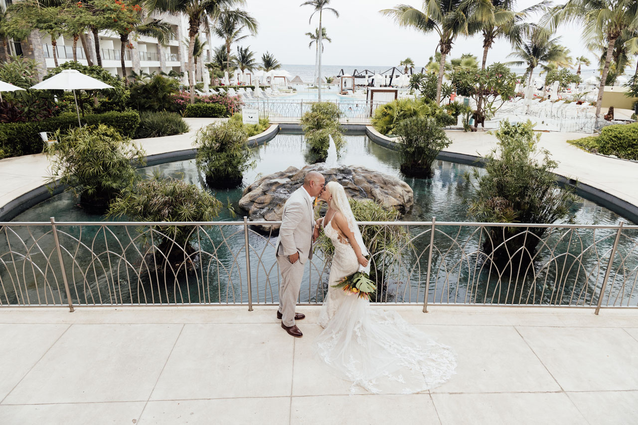 Newlyweds kiss overlooking Dreams Natura pools and beach