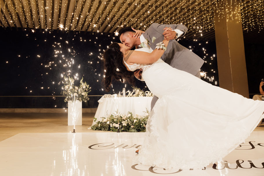Newlyweds dip in a kiss ending their first dance in a spray of sparkliers