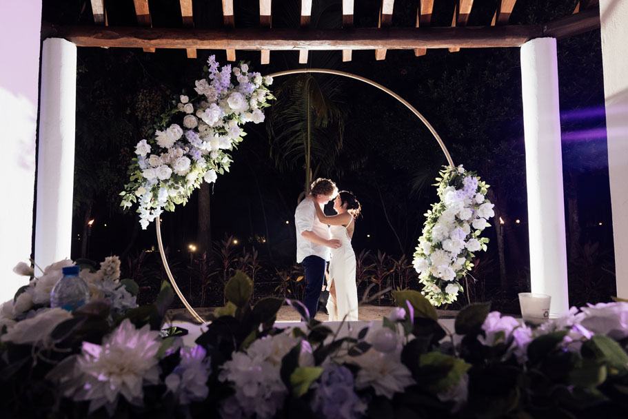 Newlyweds embrace dancing under ceremony circle adorned with elaborate flowers