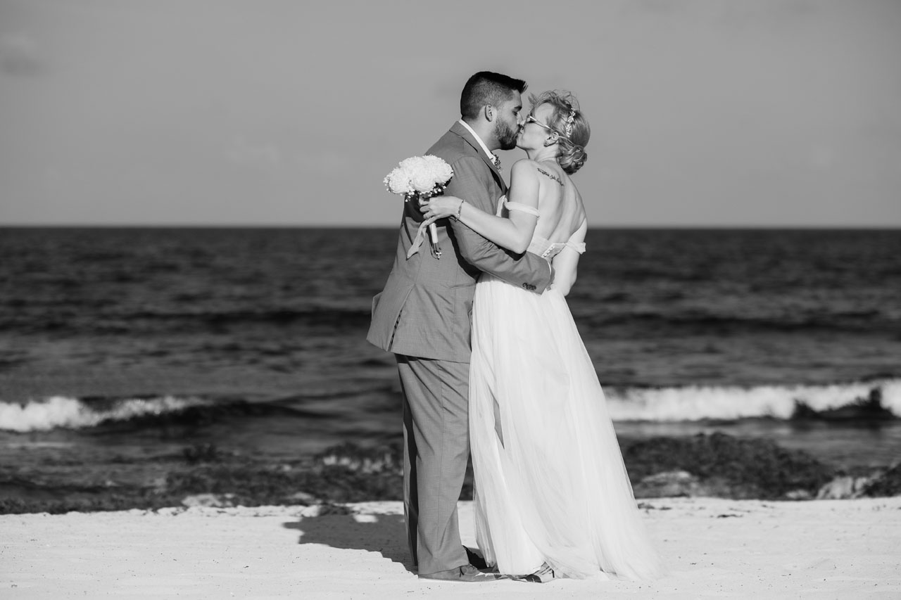Newlyweds kiss while dancing on beach