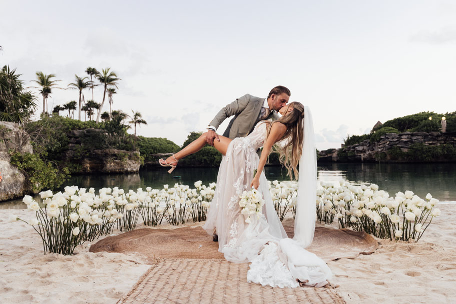 Newlywed groom dips his bride in a kiss at the edge of Xcaret's lagoon